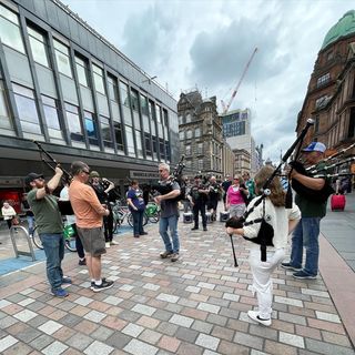 Photo by North Coast Pipe Band on August 15, 2023. May be an image of 9 people, kilt, umbrella, crowd, Rijksmuseum and street.